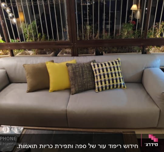 כריות צבעוניות על ספה אפורה בסלון מואר